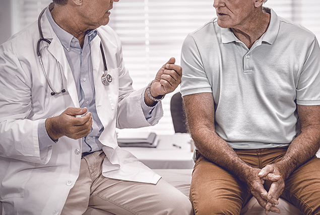 man sits on doctors table and talks with doctor in white coat