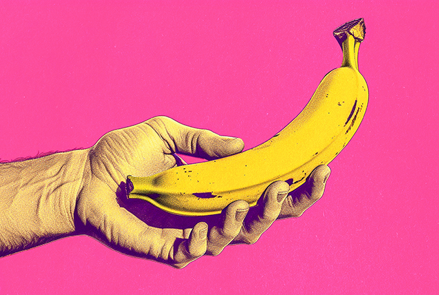 A hand holds a banana against a pink background.