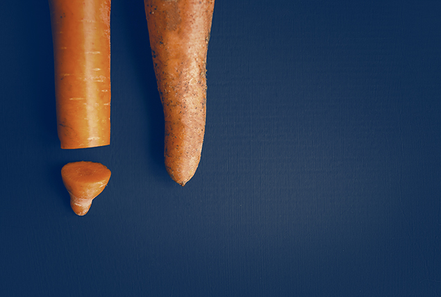 two tips of orange carrots with one with a chopped off tip on navy background