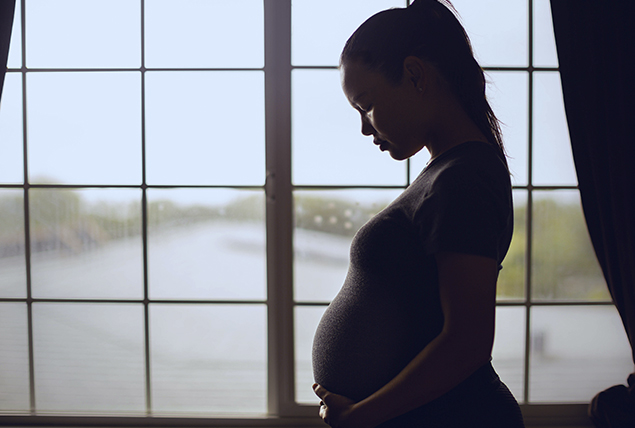 silhouette of pregnant woman in front of open window