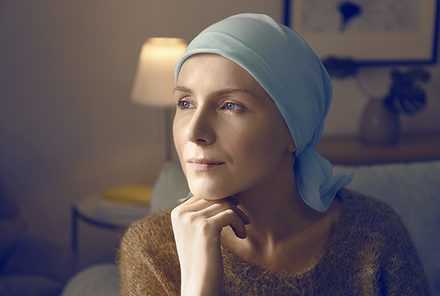 woman in light blue headscarf rests her chin on her hand and looks into the distance