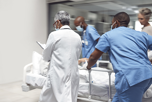 A hospital bed is rushed through the hallway by doctors and nurses.