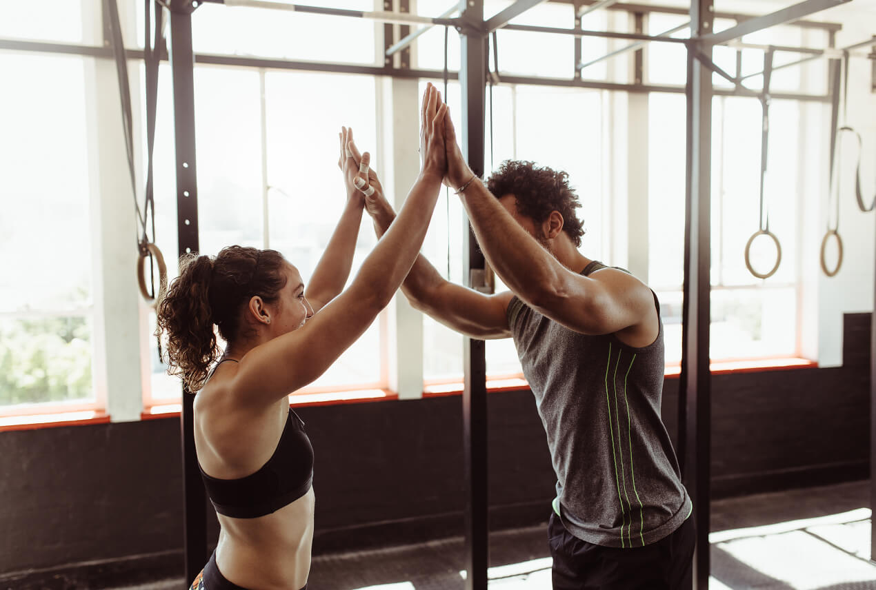 Two people at the gym double high five each other.