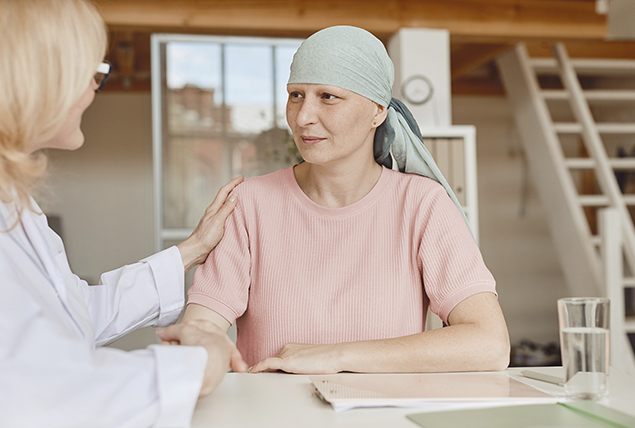 woman in mint green headscarf sits at table and is comforted by another woman