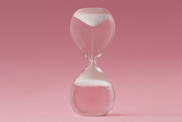 An hourglass sits on a surface as the sand reverses upwards.