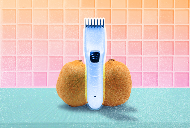two kiwis with fuzzy skin on either side of silver cordless electric clipper on orange and pink gradient tile background