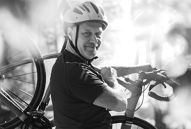 A man smiles while holding his bike.