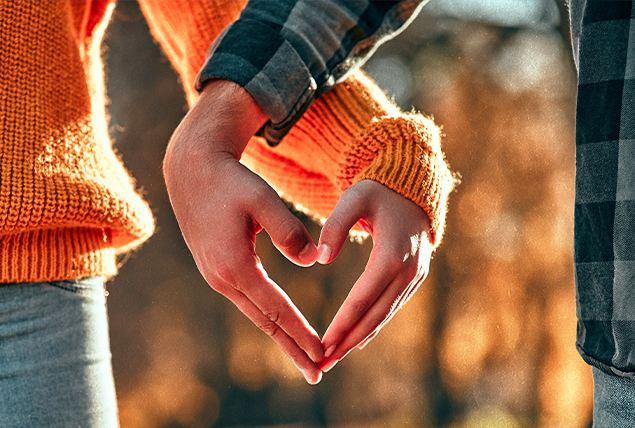 A couple puts their hands together in the shape of a heart.