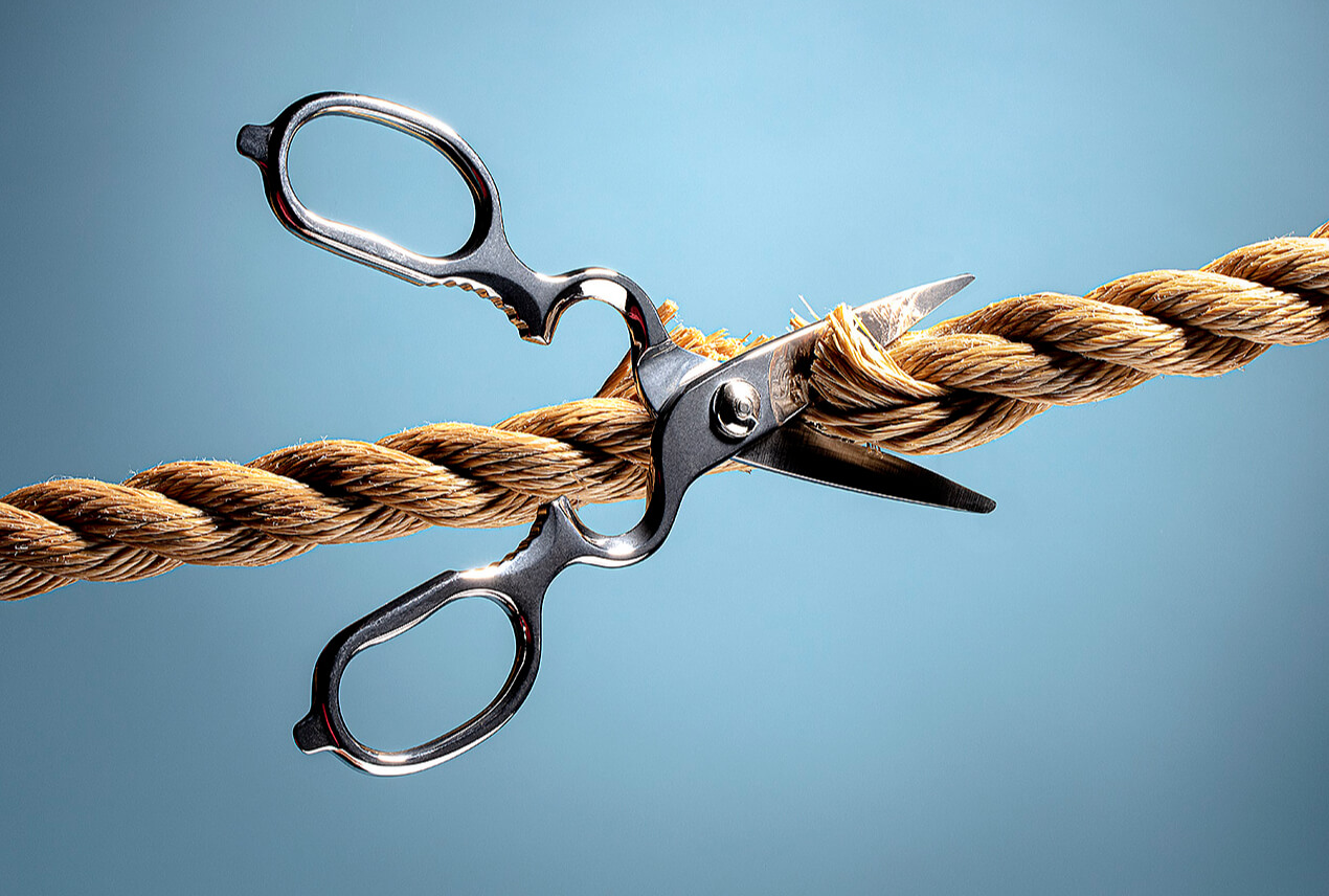 A pair of scissors cuts a rope.