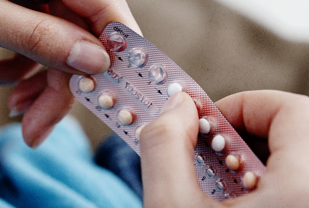 A pair of hands holds a packet of contraception pills.