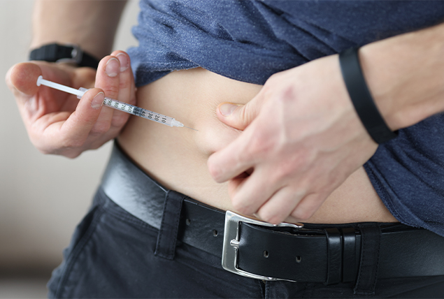A man holds a needle to his stomach as he injects himself.