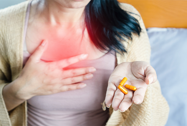 woman touches one hand to her chest that glows red while holding orange pills in other hand