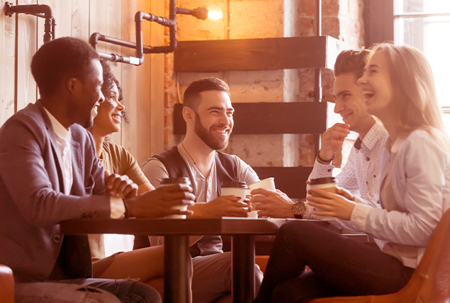 A group of people sit around a table drinking coffee.