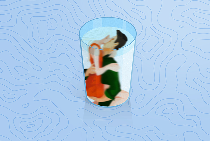 A woman is on top of a man kissing him inside of a glass of water.