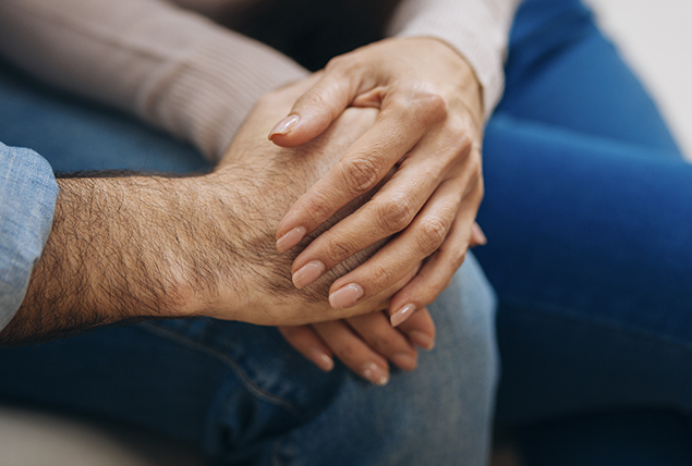 man and woman touch hands resting them on his knee
