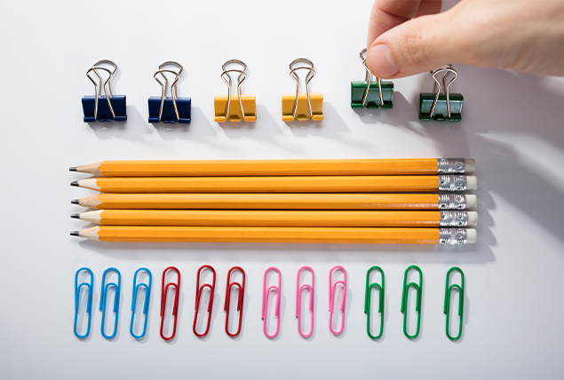 hand straightening multicolored binder clips, pencils and paper clips into straight lines