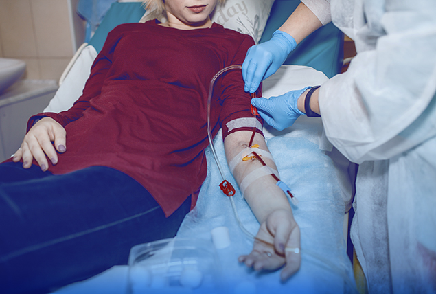 person getting blood draw by medical tech with tube coming out of their arm