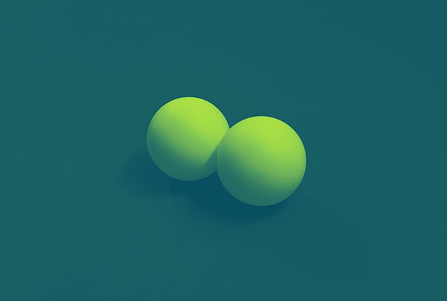 two green balls next to each other on dark teal background