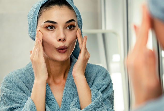A woman rubs her face after a shower.