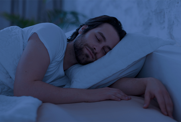 man smiles as he sleeps on his side with his face pressed into the pillow