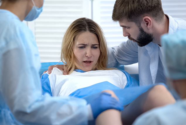 woman in childbirth pushing with male partner and doctor beside her