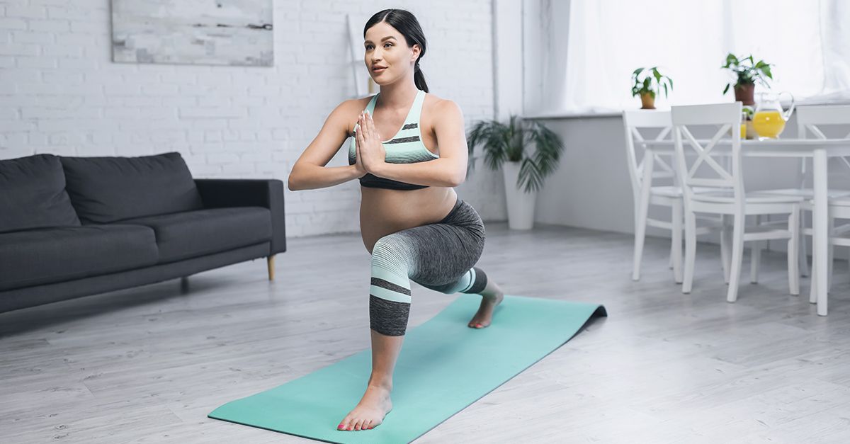 pregnant woman in workout clothes lunging in yoga pose on mint mat