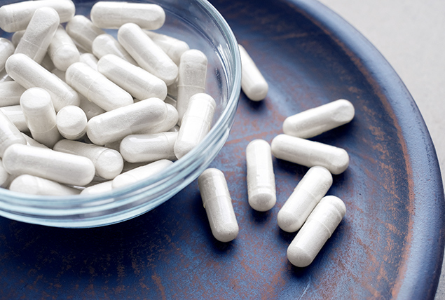 glass bowl of white supplement tablets on ceramic tray