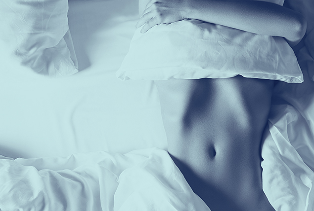 woman's bare torso on bed, wrapped in white sheets