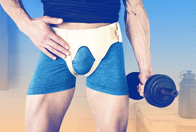 man in blue athletic shorts with hernia brace on while holding a blue dumbbell 