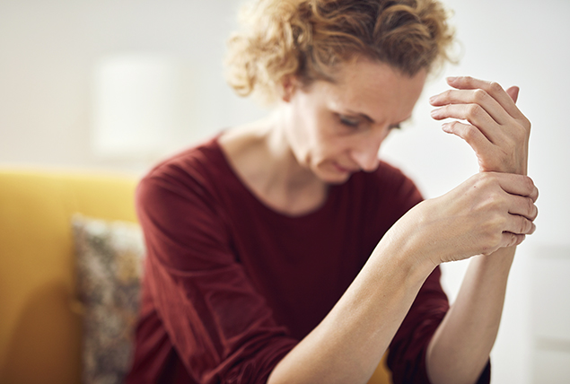 woman holds her wrist as she sits in yellow chair 