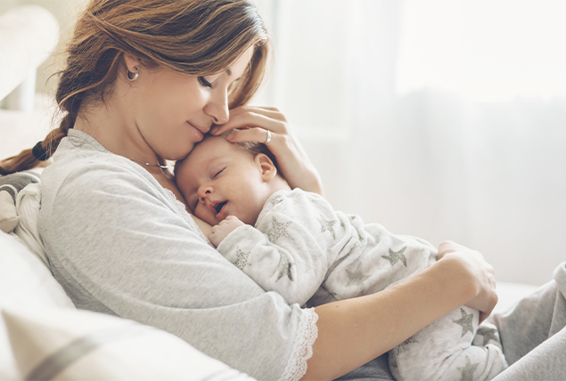 A new mom holds her newborn against her chest.