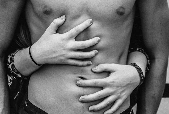 bare male torso with female hands clawing the skin from behind