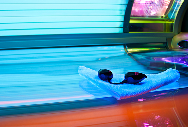 tanning bed goggles on towel resting on open tanning bed with blue light