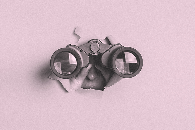 A pair of binoculars bust through a pink wall with someone looking through them.