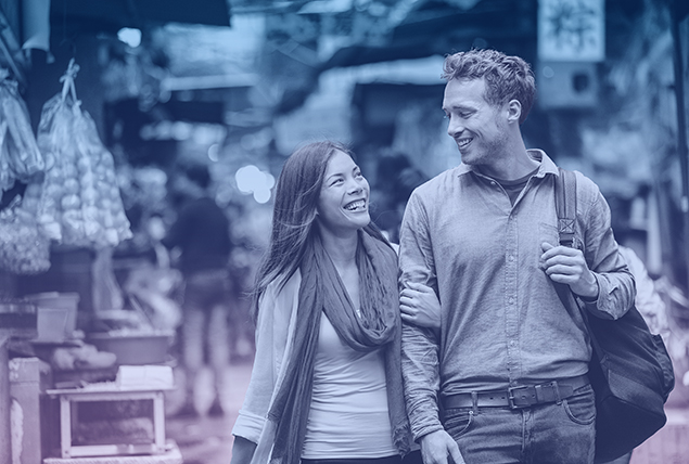 A couple walks down a market street while in a foreign country.