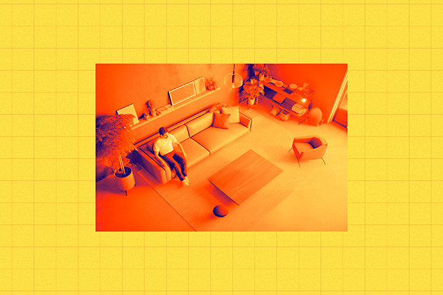A dad sits on the sofa in his home in an orange photo against a yellow background.