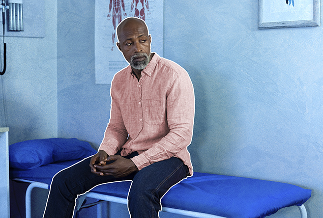 A black man sits on a hospital bed.