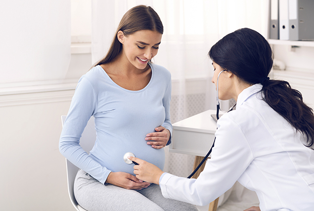 A doctor listens to a pregnant woman's belly.