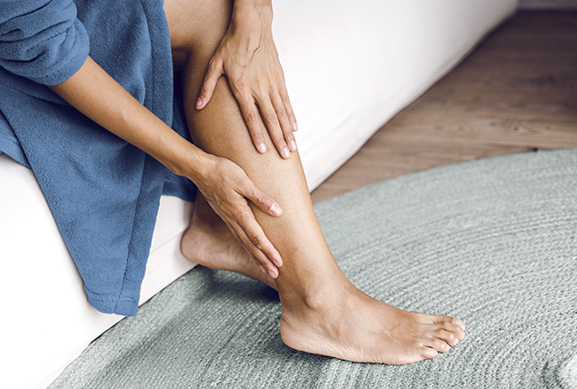 A woman reaches down to rub her hands against her calf.