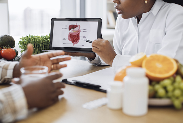 A doctor points to a tablet showing the insides of the human body.