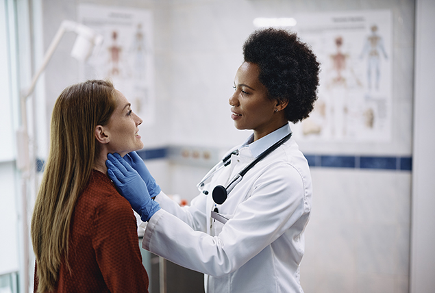 A female doctor checks the thyroid glands of a female patient.