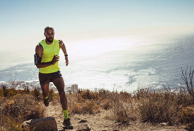 A man runs up a hill next to a body of water.