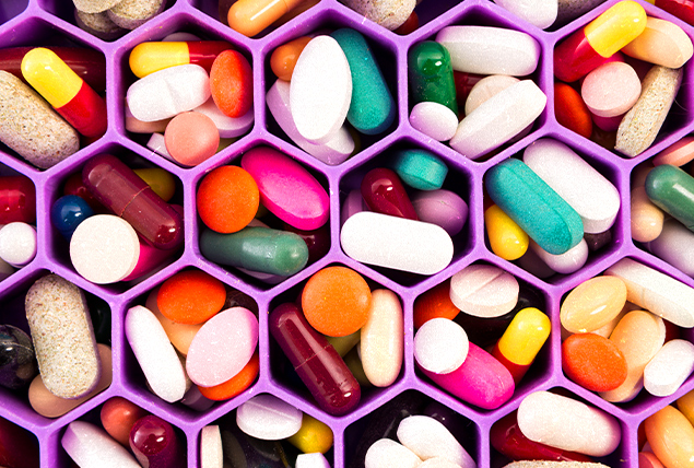 Different types of pills are inside a container with a lot of hexagon shaped barriers inside of it.