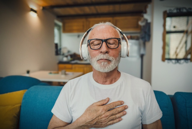 A man holds his chest while listening to music during Mens Mental Health Month.