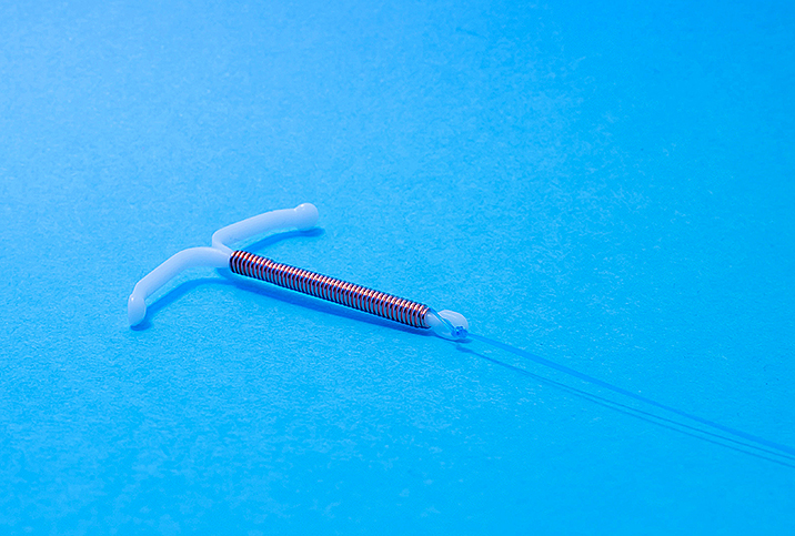 An IUD lays on a blue surface.