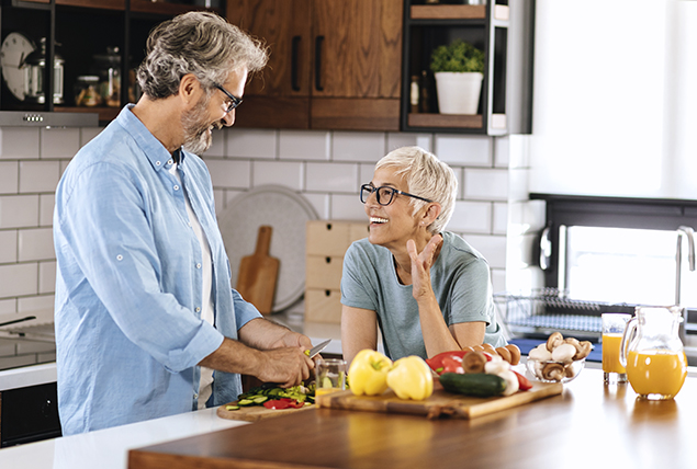 A man talks to a woman as she leans over the counter.