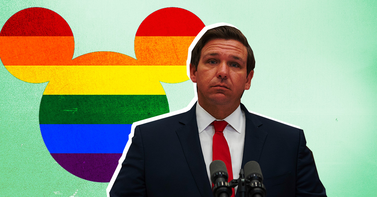 Florida Governor Ron DeSantis stands in front of rainbow-filled Mickey Mouse head.