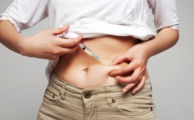 A person injecting bottom growth testosterone into their abdomen. 