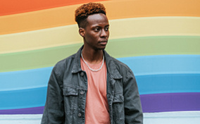 A person standing in front of a rainbow graphic.