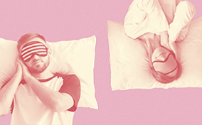 A man and woman sleep in opposite directions against a pink background.